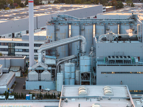 Aerial view of the BTB Blockheizkraftwerks power plant in Berlin, featuring industrial silos, piping systems, and a tall chimney stack under soft evening light in Berlin, Berlin, Germany.