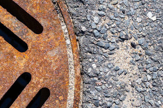 La Tuque, Quebec, 16 May 2026 : Close-up view of a rusty metal storm drain grate next to asphalt pavement.