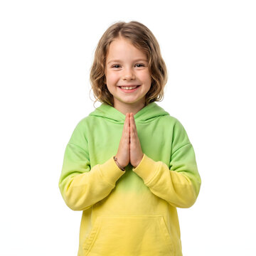 Smiling young girl in a green and yellow gradient hoodie with hands together in a namaste greeting isolated on a white background