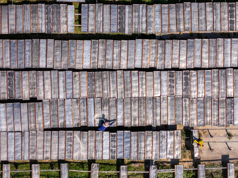 Aerial view of workers drying noodles on racks in a field in Polanharjo, Central Java, Indonesia.