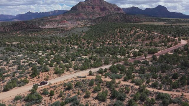 An SUV pulls a teardrop camper trailer overland on Gooseberry Mesa with Zion National Park in sight throughout the journey.