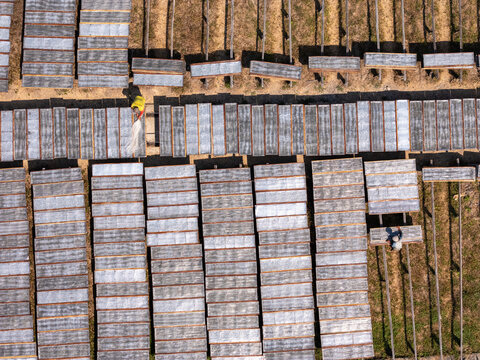 Aerial view of workers drying noodles on racks in a field in Polanharjo, Central Java, Indonesia.