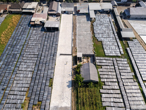 Aerial view of drying racks for traditional food products arranged in rows with a central path and surrounding buildings in Polanharjo, Central Java, Indonesia.