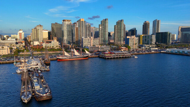 Aerial view of the San Diego skyline and waterfront, featuring historic sailing ships docked at the North Embarcadero and modern skyscrapers in San Diego, California, United States.