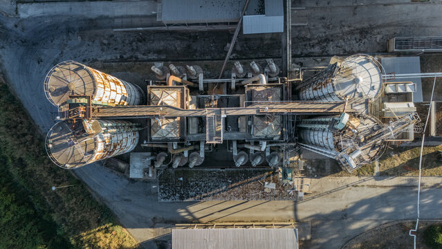 Aerial view of industrial grain silos and processing facility with metal structures, pipes, and concrete surfaces in Sremska Mitrovica, Vojvodina, Serbia.
