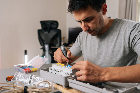 Closeup portrait of skilled handyman working on home improvement project. Man focused on power supply maintenance, showing precision and technical expertise