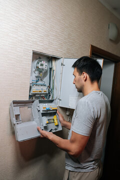 Vertical shot of electrician opening fuse box and inspecting circuit breaker panel, performing electrical maintenance, repair work for residential power supply in home