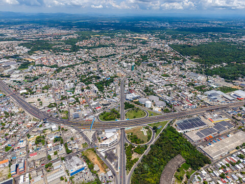 Aerial view of the Autopista Juan Pablo Duarte Km 9 interchange surrounded by urban development and industrial areas in Santo Domingo, Distrito Nacional, Dominican Republic.