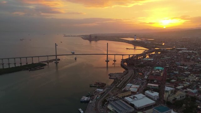 Stunning aerial footage of Cebu City and Marcelo Fernan Bridge at sunset, reflecting colorful sky over Mactan Channel.