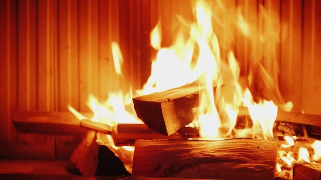 Warm fire burning with bright flames and glowing logs inside cozy fireplace for interior relaxation.