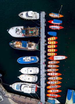 Aerial view of fishing boats and yachts moored at the pier in the Old port of Jaffa, with calm dark water and a concrete dock in Tel Aviv-Yafo, Tel Aviv District, Israel.