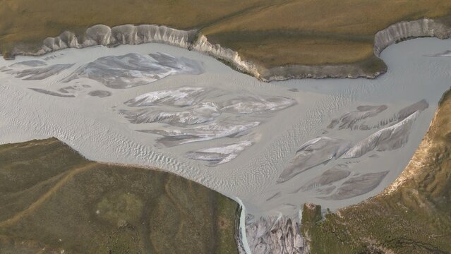 Aerial view of the braided Enilchek River with silt-laden glacial water flowing through the rugged landscape of the Tian Shan mountains in Enilchek, Issyk-Kul Region, Kyrgyzstan.