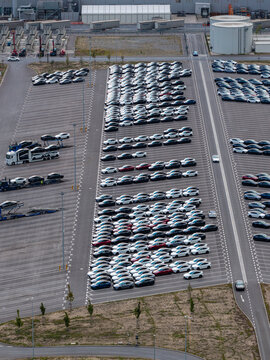Aerial view of the Tesla Gigafactory Berlin-Brandenburg parking lot filled with rows of new electric vehicles and transport trucks in Grunheide Mark, Brandenburg, Germany.