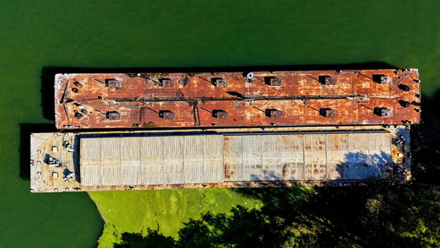 Aerial view of two industrial barges moored on the Danube river, one with a rusted metal deck and the other with a covered cargo hold in Smederevo, Podunavlje District, Serbia.