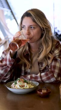 Woman drinking beer beside fresh salad in a restaurant, creating a calm mood of pause, taste, and social ease