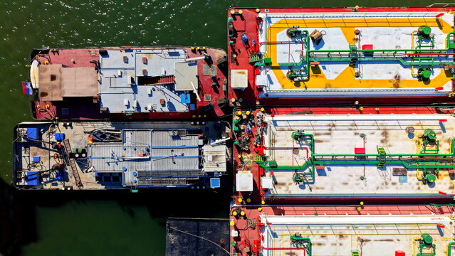 Aerial view of industrial barges and cargo ships docked at the Smederevo shipyard, showcasing detailed deck structures and piping on the Danube river in Smederevo, Podunavlje District, Serbia.
