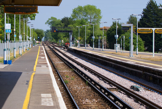 Scenic empty train station platform and railway tracks in England.