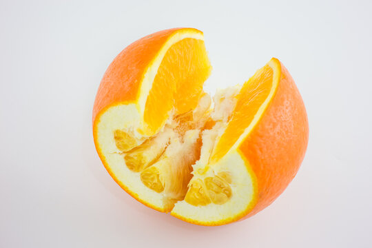 A partially consumed fresh orange, cut to show its inner segments, placed on a plain white background.