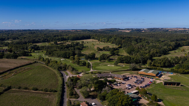 Aerial view of Hamptworth Golf course with lush green fairways, sand bunkers, surrounding woodland, and the clubhouse with a parking lot in Hamptworth, England, United Kingdom.