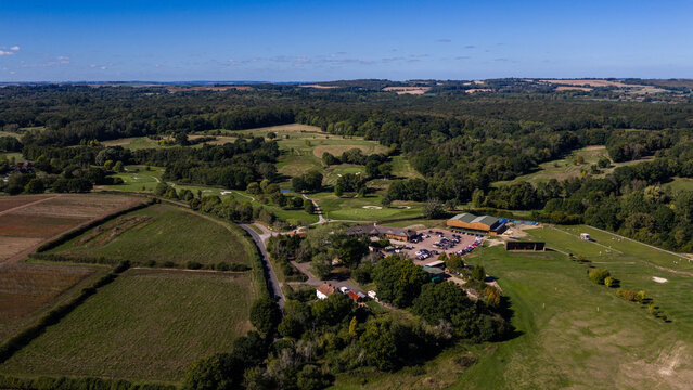 Aerial view of Hamptworth Golf course featuring the clubhouse, parking area, and sprawling green fairways surrounded by dense woodland in Hamptworth, England, United Kingdom.