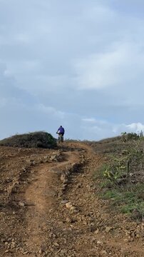 The cyclist is riding his bicycle up the hill with great effort in a rural area of ​​Margarita Island, Venezuela.