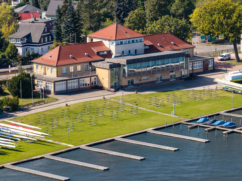 Aerial view of Berlin-Grunau Regatta Course with its historic clubhouse, rowing boats on the lawn, and floating docks on the Dahme river in Berlin, Berlin, Germany.