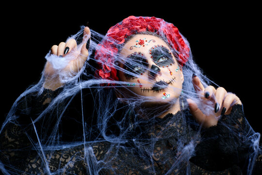 Halloween beauty portrait of woman. Female face with Santa Muerte makeup and entangled in old web.