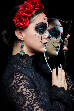 Halloween beauty portrait of woman with Santa Muerte makeup. Female with a shard of the mirror.