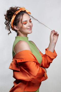 Young woman with curly hair and hairband holds a strand of hair in hand.