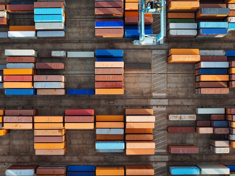 Aerial view of the semi-automated container port featuring rows of colorful shipping containers and automated storage yard infrastructure in Vado Ligure, Liguria, Italy.