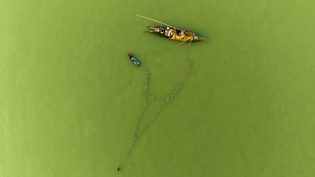 Aerial view of local fishermen working with traditional wooden boats and fishing nets on the river in Pabna, Rajshahi Division, Bangladesh.