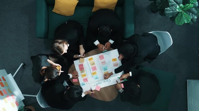 Top down view of business people hands making scrum task board to manage workflow in workplace. Diverse marketing team drawing a line and use colorful stick notes to work on kanban. Directorate.