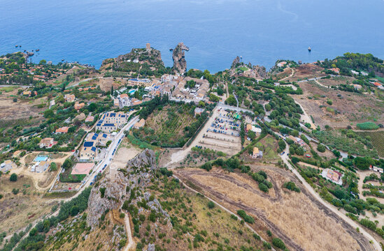 Aerial view of Riserva Naturale Orientata dello Zingaro with rugged coastal cliffs, Mediterranean vegetation, and historic stone structures near the sea in San Vito Lo Capo, Sicilia, Italy.
