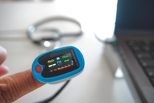 Patient using a pulse oximeter for remote health monitoring, showing spo2 and prbpm values