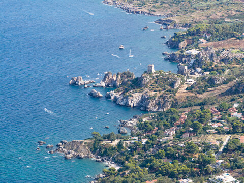 Aerial view of the rugged coastline of Riserva Naturale Orientata dello Zingaro featuring turquoise sea, historic watchtower, and Mediterranean vegetation, San Vito Lo Capo, Sicilia, Italy.