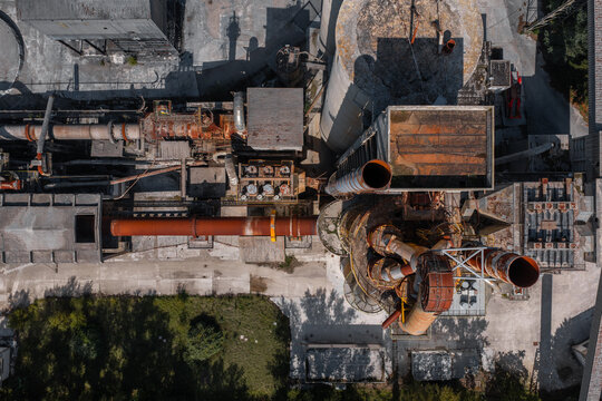 Aerial view of the Sacci S.P.A. cement factory featuring industrial pipes, tall silos, and rusted metal structures in Castelraimondo, Marche, Italy.
