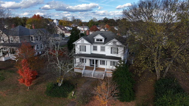 Aerial view of a white residential house with a front porch, surrounded by autumn trees and a suburban neighborhood in Altavista, Virginia, United States.