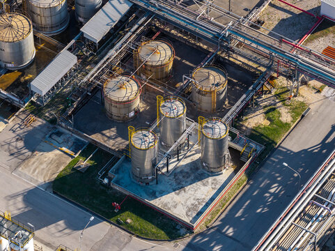 Aerial view of an industrial facility featuring large cylindrical storage tanks, complex piping networks, and concrete surfaces in Nera Montoro, Umbria, Italy.