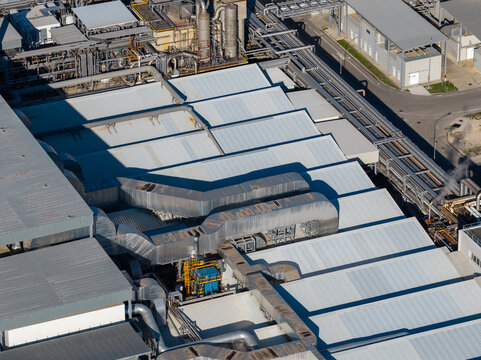 Aerial view of an industrial facility featuring large corrugated metal roofs, complex ventilation ductwork, and pipes in Nera Montoro, Umbria, Italy.