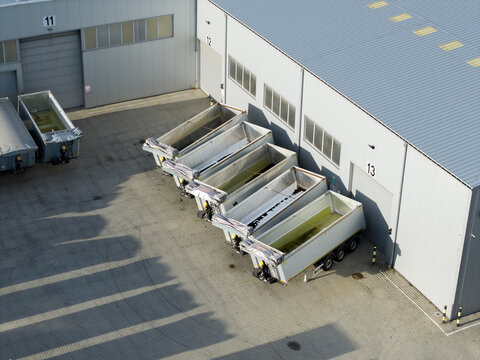 Aerial view of empty semi-trailers parked in a row outside a modern industrial warehouse facility with numbered loading bays in Krakow, Lesser Poland Voivode, Poland.