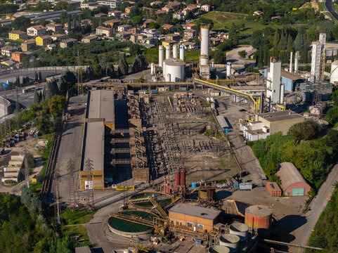 Aerial view of the Acciai Speciali Terni S.p.A. industrial steel plant featuring large storage tanks, processing buildings, and power infrastructure in the outskirts of Terni, Umbria, Italy.