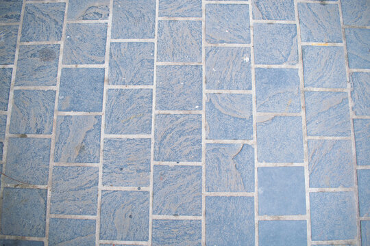 a surface of blue-grey natural stone paving tiles with a textured, linear pattern and light mortar joints, resembling slate or bluestone pavers.