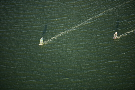 Aerial view of two windsurfers gliding across the deep green waters of Guanabara Bay in Rio de Janeiro, Rio de Janeiro, Brazil.