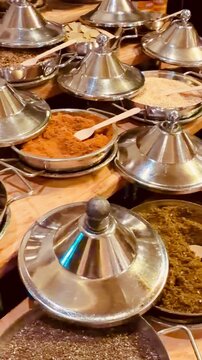 Vertical display of traditional oriental spices and vibrant aromatic herbs in metal tajine bowls at a luxury 5-star hotel buffet in Sharm El Sheikh, Egypt. All-inclusive gourmet dining.
