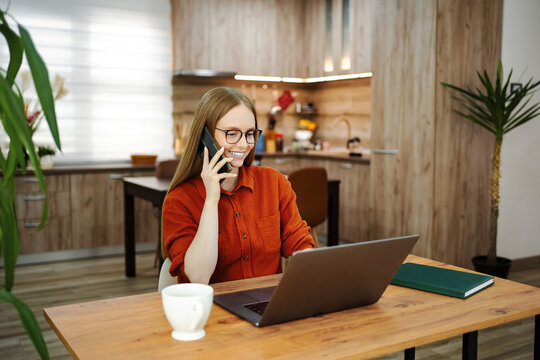 Woman multitasking working remotely from home on laptop and phone