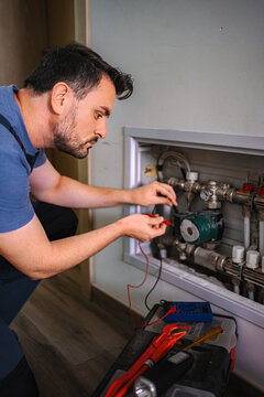 Technician checking heating system pressure with multimeter