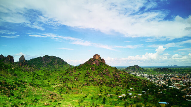 Aerial view of the rocky hills of Dass surrounded by lush green vegetation and the outskirts of the town in Bauchi, Bauchi, Nigeria.