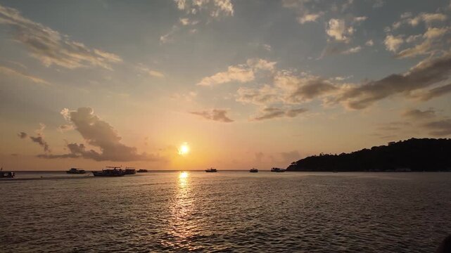 Stunning golden sunset over tropical ocean with silhouette boats anchored at dusk cinematic vacation footage.