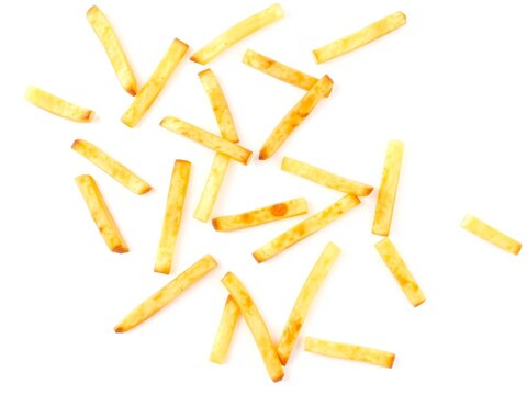 Top view of crispy golden french fries scattered on a flat surface