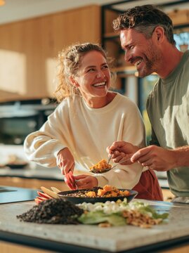 Couple preparing a healthy salad together, laughing and sharing a joyful moment